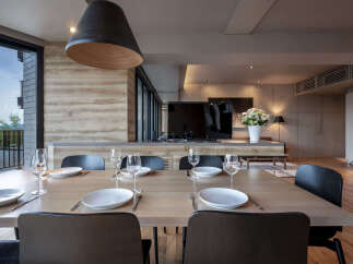 Experience modern living in this stunning dining area, featuring a sleek wooden table set for an intimate meal.