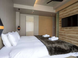 Experience modern comfort in this stylish bedroom, featuring a plush king-sized bed adorned with crisp white linens and a luxurious faux fur throw.