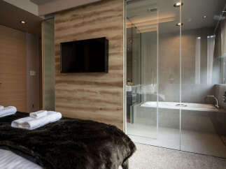Experience modern luxury in this hotel room featuring a spacious bed with plush bedding and a sleek, wall-mounted television.