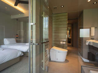 Experience luxury and comfort in this modern hotel room featuring two plush beds and a sleek, spa-like bathroom.