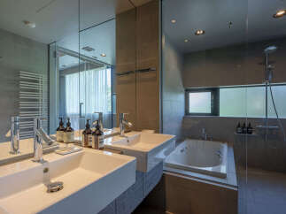 Experience modern luxury in this stunning bathroom featuring dual vessel sinks and a sleek, freestanding bathtub.