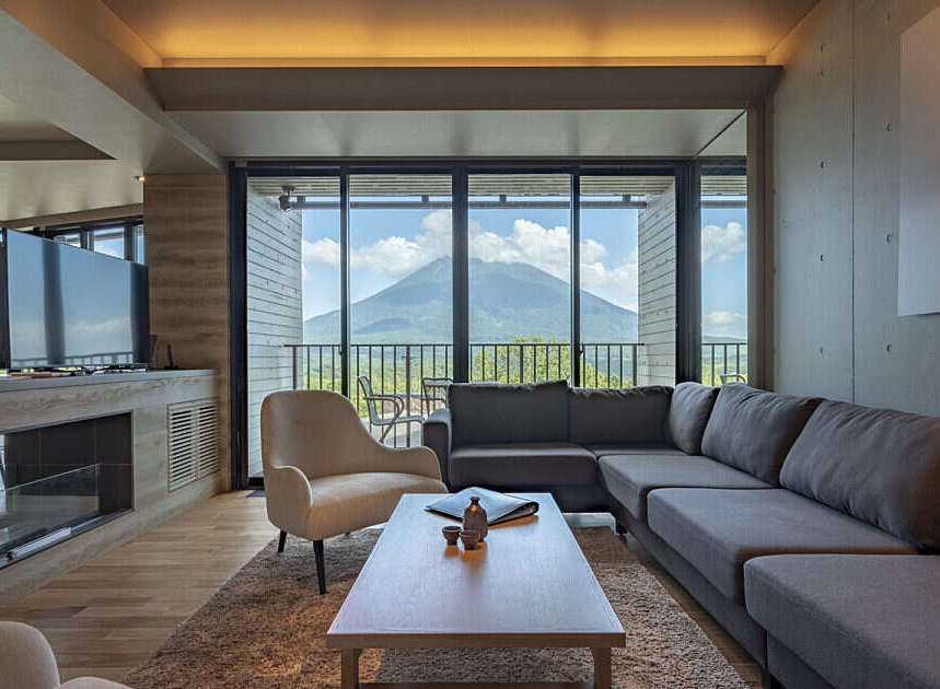 Experience breathtaking mountain views from this luxurious living room, featuring a spacious sectional sofa and a comfortable armchair.