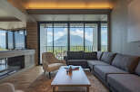 Experience breathtaking mountain views from this luxurious living room, featuring a spacious sectional sofa and a comfortable armchair.