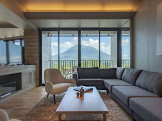 Experience breathtaking mountain views from this luxurious living room, featuring a spacious sectional sofa and a comfortable armchair.