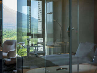 Experience luxury living with this stunning hotel room featuring a spacious bathtub and a comfortable armchair, perfect for relaxation.