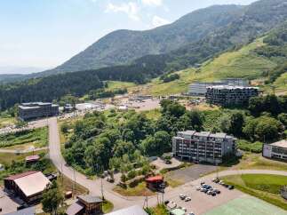 Discover this stunning mountain resort property, featuring modern multi-story buildings nestled amidst lush greenery and rolling hills.