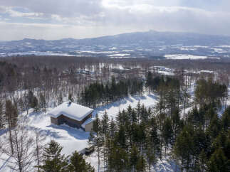 Experience serene winter living in this picturesque property nestled amidst snow-covered trees and rolling hills.