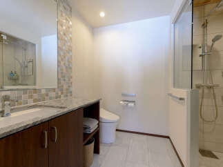 This modern bathroom features a sleek vanity with a granite countertop and a vessel sink, complemented by a stylish mosaic tile backsplash.