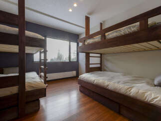 This spacious bedroom features two sets of sturdy wooden bunk beds, perfect for accommodating multiple guests or a large family.