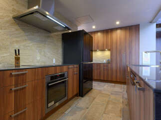Experience modern luxury in this stunning kitchen, featuring sleek wooden cabinetry and a sophisticated marble backsplash.