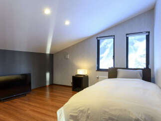 Experience comfort and style in this modern attic bedroom, featuring a cozy bed with crisp white linens and a plush pillow.