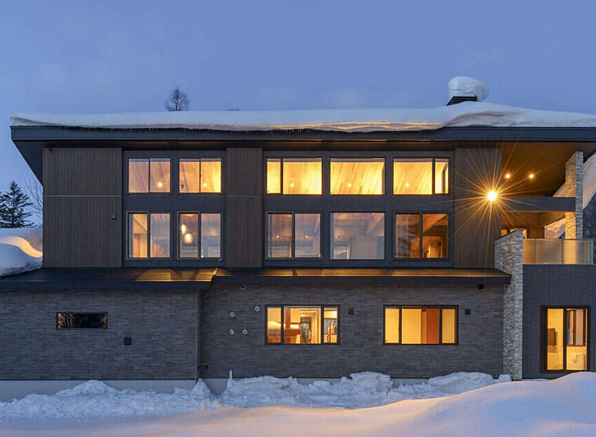 Experience luxury living in this modern mountain home, nestled amidst a serene winter landscape.