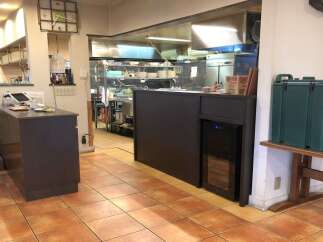 Discover the operational heart of this establishment, featuring a well-equipped kitchen with stainless steel appliances and ample storage.