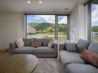 Experience breathtaking mountain views from this modern living room, featuring comfortable grey sofas and a stylish wooden coffee table.