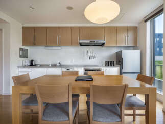 This modern kitchen and dining area features sleek wooden cabinetry and a spacious dining table perfect for family meals.