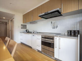 Experience modern living in this sleek kitchen featuring clean white cabinetry and warm wood accents.