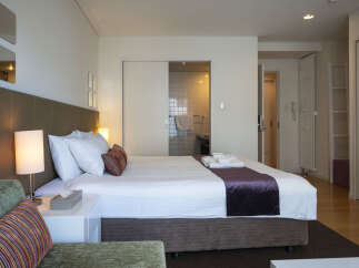 Experience comfort and style in this well-appointed hotel room, featuring a plush king-sized bed with crisp white linens and decorative pillows.
