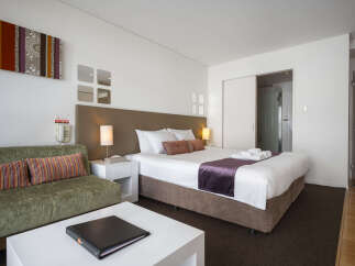 Experience comfort and style in this well-appointed hotel room, featuring a plush king-sized bed adorned with crisp white linens and a luxurious purple accent runner.