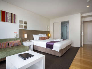 Experience comfort and style in this well-appointed hotel room, featuring a plush king-sized bed with luxurious linens and a decorative purple runner.
