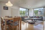 Experience modern living in this spacious apartment featuring a combined dining and living area with large windows offering scenic views.