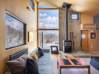 Experience cozy living in this modern mountain retreat, featuring a striking wood-paneled interior and a large window offering breathtaking snowy landscape views.