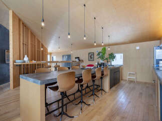 Experience modern living in this stunning open-concept space featuring a sleek concrete dining table with comfortable leather stools, perfect for entertaining.