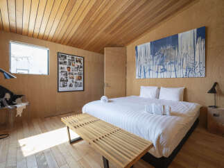 Experience modern comfort in this beautifully designed bedroom, featuring warm wood paneling throughout and a striking abstract art piece.