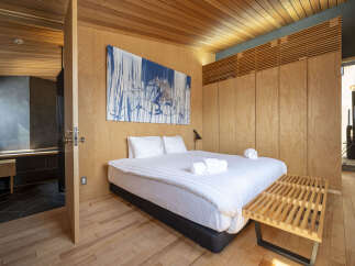 Experience modern luxury in this beautifully appointed bedroom, featuring a king-sized bed with crisp white linens and a striking abstract artwork.