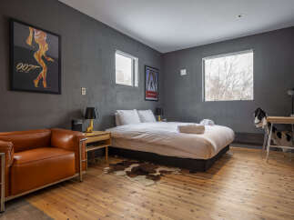 Experience a unique stay in this stylish bedroom featuring a comfortable bed, a chic orange leather armchair, and a modern desk area.