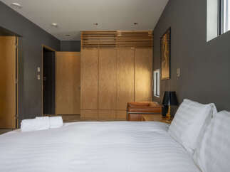 Experience modern comfort in this stylish bedroom, featuring a plush bed with crisp white linens and a sleek leather armchair.