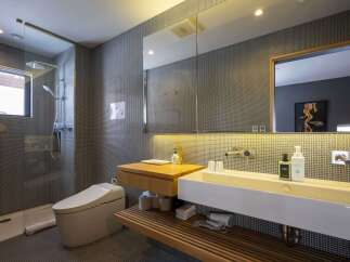 Experience modern luxury in this sleek bathroom featuring a spacious walk-in shower with a rainfall showerhead and a bidet toilet.