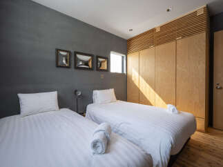 This modern bedroom features two comfortable twin beds with crisp white linens, perfect for a restful night's sleep.