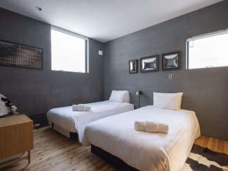 Experience modern comfort in this stylish bedroom featuring two twin beds with crisp white linens and plush pillows.