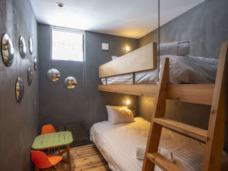 Discover this modern and cozy room featuring a space-saving bunk bed, perfect for maximizing comfort and utility.