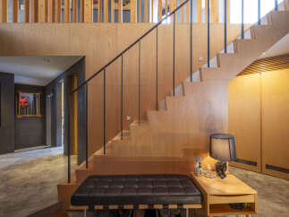 Experience modern living with this stunning staircase featuring warm plywood finishes and sleek black railings.