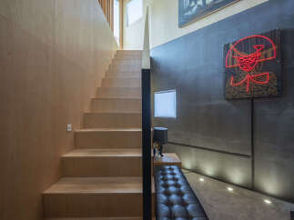 Ascend a modern staircase with warm plywood finishes, leading to a bright upper level.