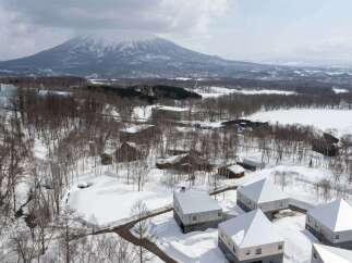 Discover modern architectural marvels nestled in a serene winter landscape, featuring contemporary homes with unique pyramidal roofs and sleek wooden exteriors.
