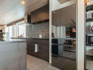 Experience modern living in this sleek kitchen featuring a mirrored refrigerator and dark wood cabinetry.