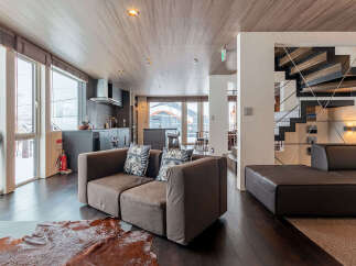Experience modern living in this spacious open-concept home, featuring a sleek kitchen with dark cabinetry and a stainless steel range hood.