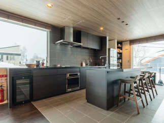 Experience modern living in this sleek kitchen featuring dark cabinetry, a stainless steel range hood, and a spacious island with bar seating.
