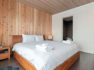 Experience serene living in this beautifully appointed bedroom, featuring warm wooden walls and ceiling that create a cozy, natural ambiance.