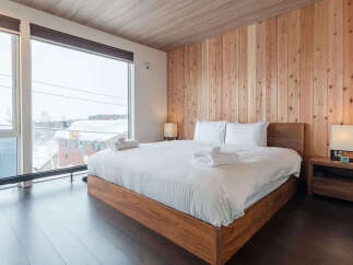 Experience ultimate comfort in this modern bedroom featuring a plush king-size bed with crisp white linens and fluffy towels.