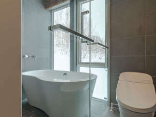 Experience ultimate relaxation in this luxurious bathroom featuring a deep soaking tub with a stunning view of the winter landscape through large windows.