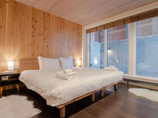 Experience modern comfort in this beautifully appointed bedroom featuring warm wood paneling and a plush king-sized bed.