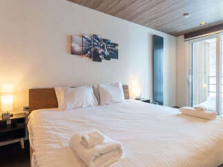 Experience ultimate comfort in this beautifully appointed bedroom, featuring a plush king-sized bed with crisp white linens and soft pillows.