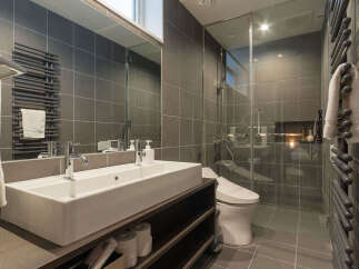Experience modern luxury in this sleek bathroom featuring a spacious double vanity with contemporary faucets and a wall-mounted towel warmer.