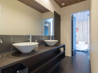 This modern bathroom features a spacious double vanity with two vessel sinks and sleek chrome faucets, set against a dark tiled backsplash.