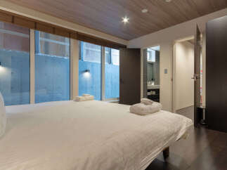 Experience modern comfort in this stylish bedroom featuring a plush bed adorned with fresh towels.