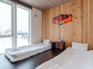 Experience cozy winter living in this charming room featuring two comfortable beds and large windows offering picturesque snow-covered views.