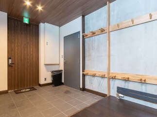 Discover a welcoming entryway featuring a stylish wooden door with modern hardware and an illuminated exit sign for safety.